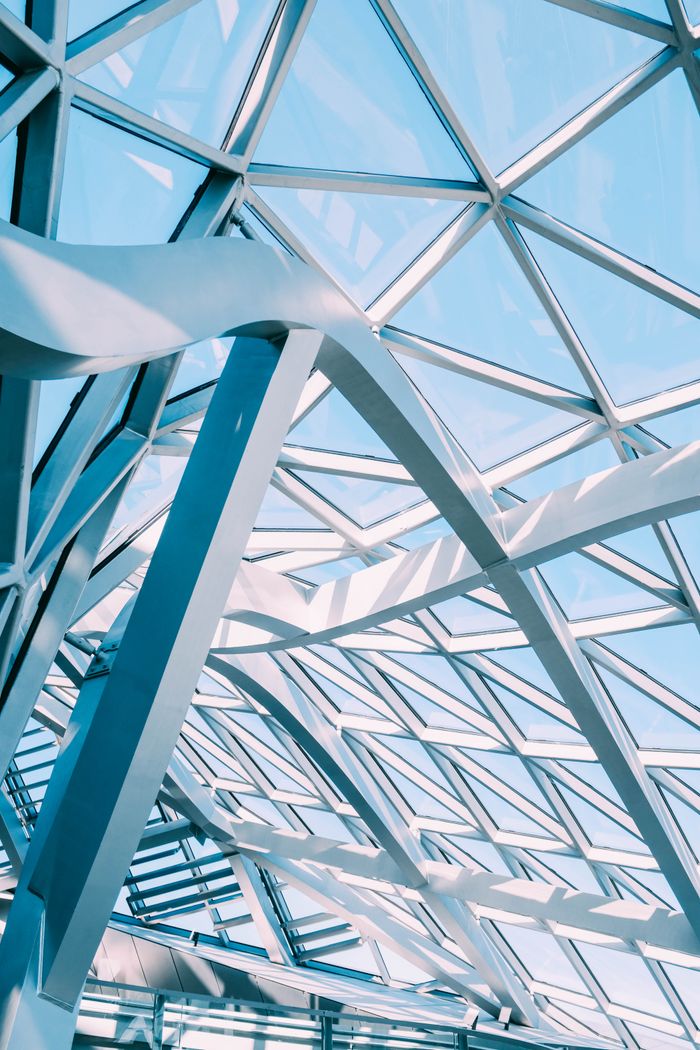 Abstract view of a modern glass and metal ceiling with geometric patterns and sunlight reflection.